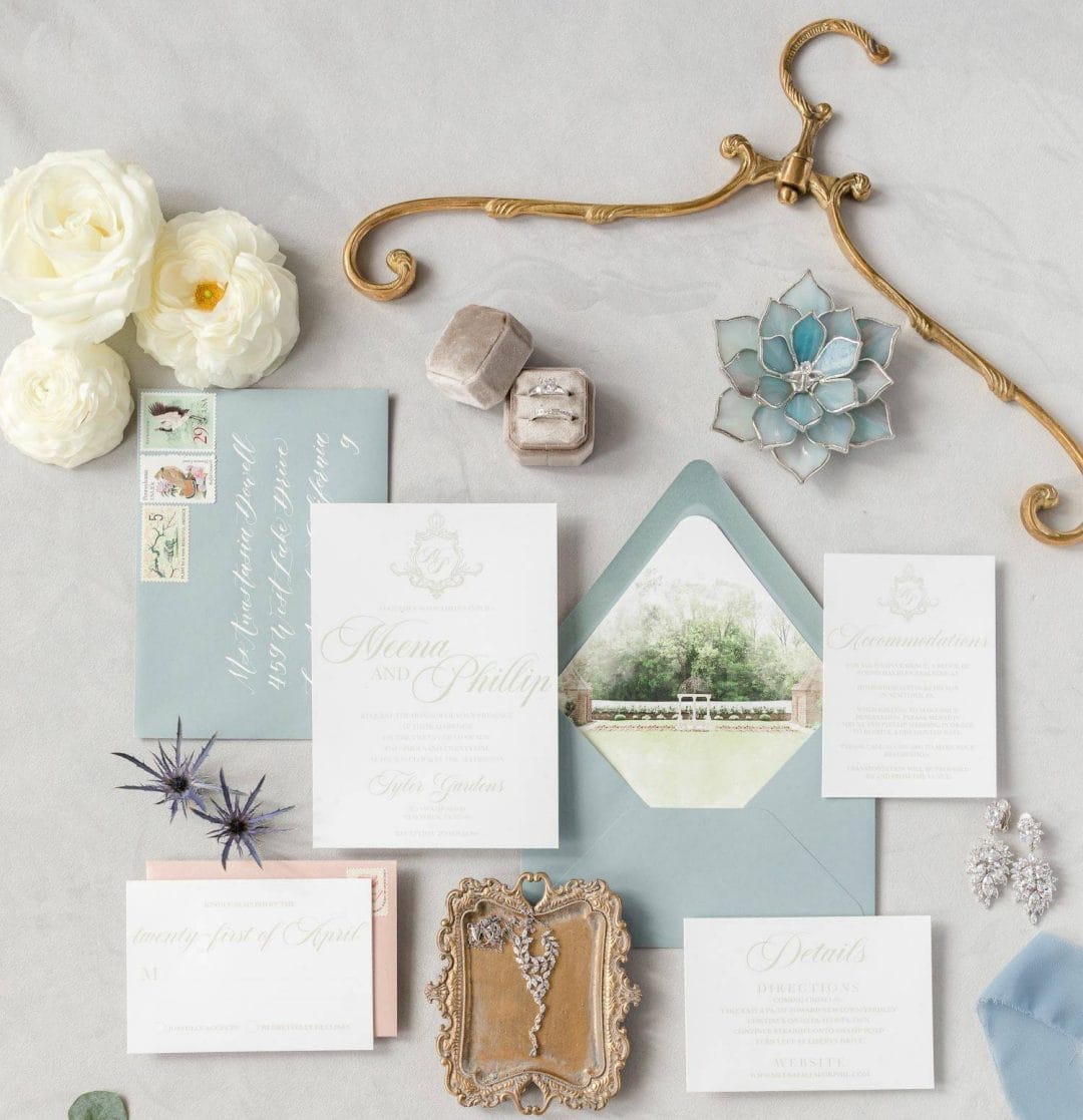 A dusty blue and white wedding stationery set on a marble table.